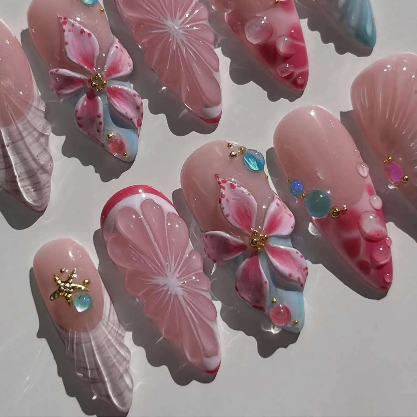 Decorative false nails with pink flowers, starfish and seashell