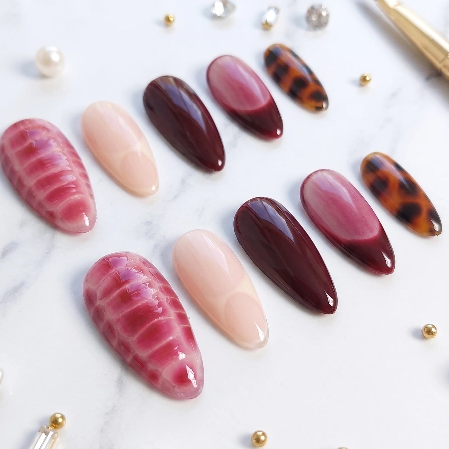 Set of nail art designs with pink, red, and brown colors on a white background.