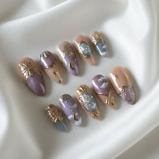 Set of decorative false nails with purple and gold designs in a clear case.