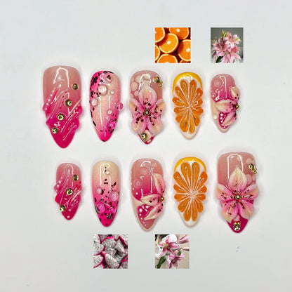 A set of 10 luxury hand-painted press-on nails featuring 3D pink lilies, textured orange pulp slices, and dragon fruit patterns with realistic clear 3D juice droplets and gold accents